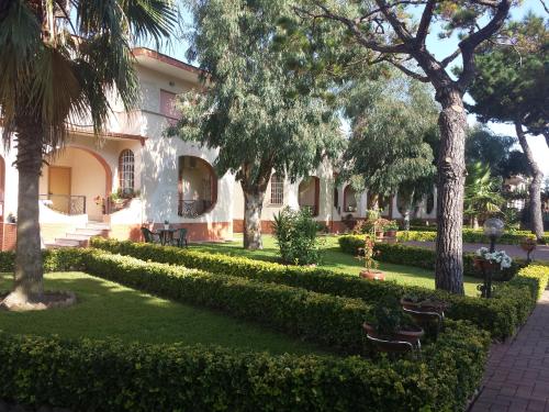 um edifício com árvores e um relvado em frente em Thairè Resort em Castel Volturno