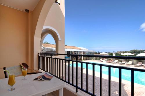 balcone con tavolo e vista sulla piscina di Makris Apartments Arillas Corfu a Arillas