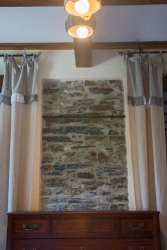 a stone wall in a room with curtains and a dresser at B&B Terre e Colori in Sant'Olcese