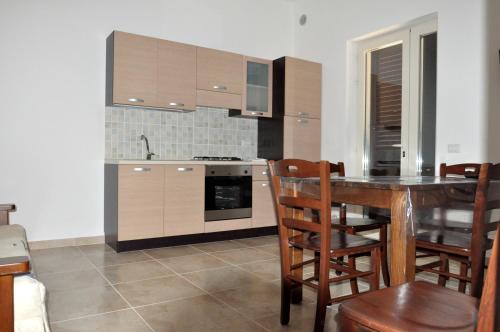 a kitchen with a table and wooden cabinets and a table and chairs at Casa Vacanze Eufemia in Giurdignano