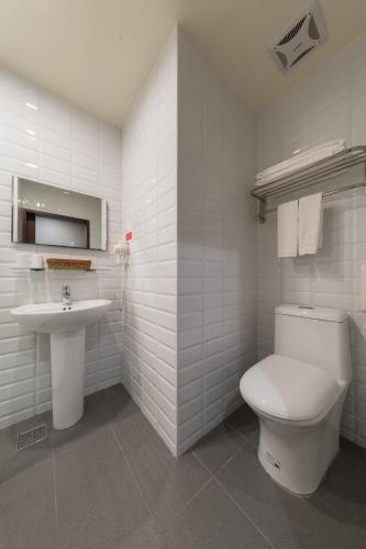 a white bathroom with a toilet and a sink at Skyone Hotel in Kaohsiung