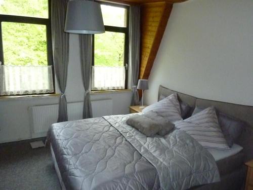 een slaapkamer met een wit bed en 2 ramen bij Ehemaliges Waldkurhaus Drangstedt in Drangstedt