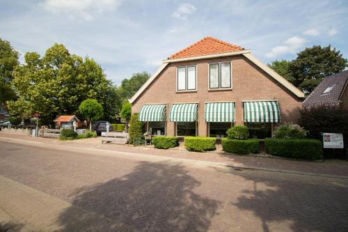 a brick house with green awnings on a street at B&B Aangenaam - Olde Horst Diever in Diever