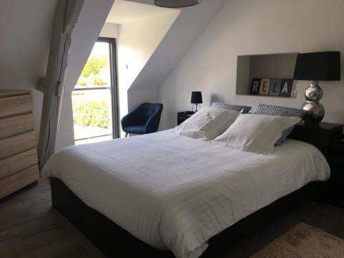 1 dormitorio con 1 cama blanca grande y 1 silla en Loft P'tite Pomme Azay le Rideau en Azay-le-Rideau