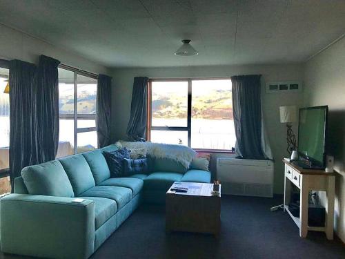 een woonkamer met een blauwe bank en een televisie bij Harbour Side Views in Dunedin