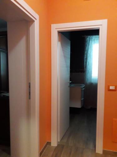 baño con pared de color naranja y puerta abierta en B&B Arcobaleno, en Penna SantʼAndrea