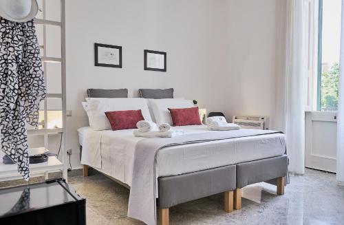 una camera da letto con un grande letto con lenzuola bianche e cuscini rossi di Dimora Casanello a Lecce