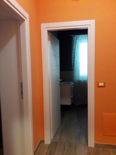 Habitación naranja con puerta que conduce a un baño en B&B Arcobaleno, en Penna SantʼAndrea