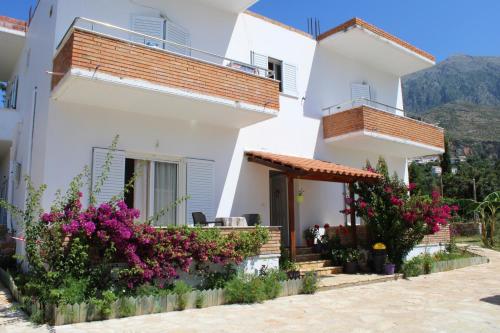 a white house with flowers in front of it at Penelope's Rooms in Dhërmi