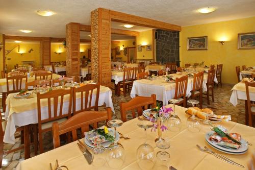 una sala da pranzo con tavoli e sedie bianchi di Hotel Holiday Debili a Sauze d'Oulx