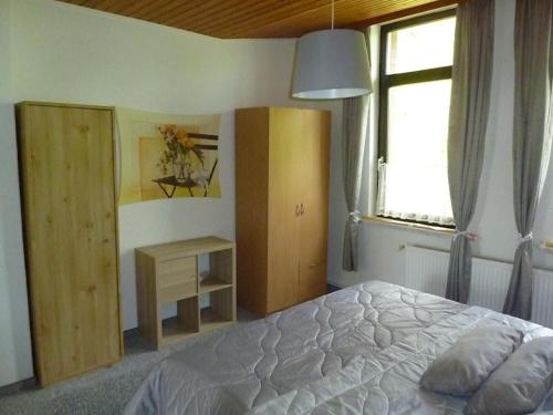 a bedroom with a bed and a desk and a window at Ehemaliges Waldkurhaus Drangstedt in Drangstedt