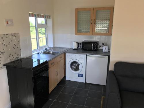 una pequeña cocina con lavadora y fregadero en Moorhouse Farm Flat, en Telford