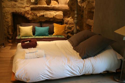 a large bed in a room with a stone wall at Le domaine des rouges queues in Châteaudouble