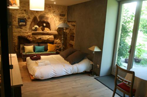 a bed in a room with a stone wall at Le domaine des rouges queues in Châteaudouble