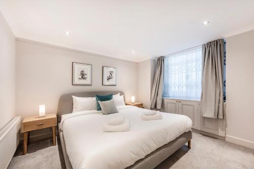 a bedroom with a large white bed and a window at Stylish 2 bedroom flat in Knightsbridge in London