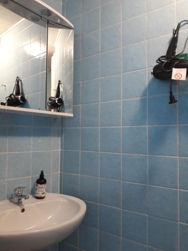 ein blau gefliestes Bad mit einem Waschbecken und einem Spiegel in der Unterkunft Rathausschenke Münstermaifeld in Münstermaifeld