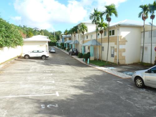 a car parked in a parking lot with palm trees at appartement les pieds dans l'eau dans résidence de standing in Le Diamant