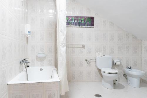y baño blanco con aseo y bañera. en Alojamiento Calzada Romana, en Belmonte de Miranda
