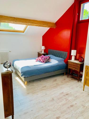 a bedroom with a bed with a red wall at La gentilhommiere de Saumur in Saumur