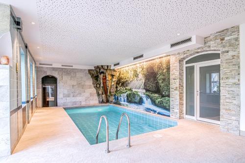 a swimming pool in a house with a waterfall mural at Alpin Hotel Gudrun in Colle Isarco