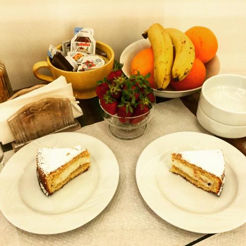 two slices of cake on plates on a table with fruit at Ai Tre Mercati in Palermo