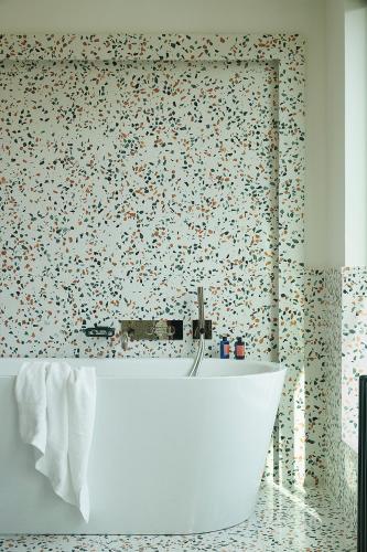 a bathroom with a white tub and a patterned wall at Hôtel Le Ballu in Paris