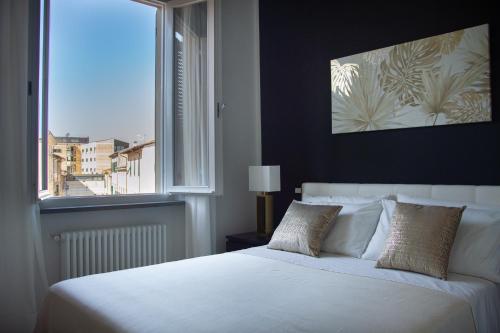 um quarto com uma grande cama branca e uma janela em AMA Casa em Pisa