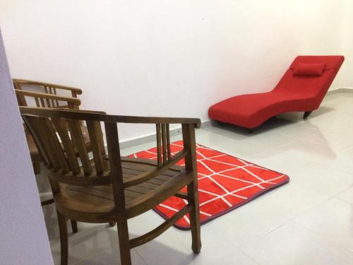 a wooden chair and a red stool in a room at Sesuci Murni Homestay in Tanah Merah
