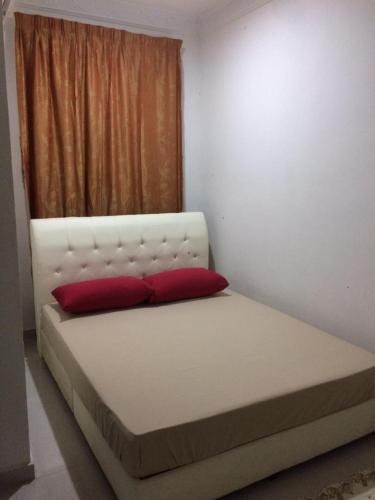 a bed with two red pillows in a room at Sesuci Murni Homestay in Tanah Merah