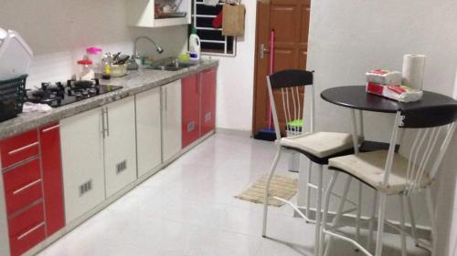 a kitchen with red cabinets and a table and chairs at Sesuci Murni Homestay in Tanah Merah
