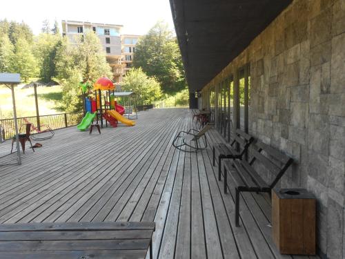 eine Holzterrasse mit Bänken und einem Spielplatz in der Unterkunft Apart Hotel ART in Bakuriani