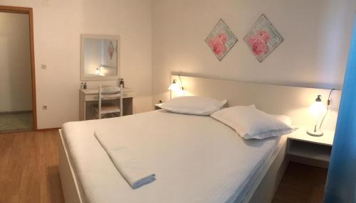 a bedroom with a white bed with two pillows at Green house in Makarska