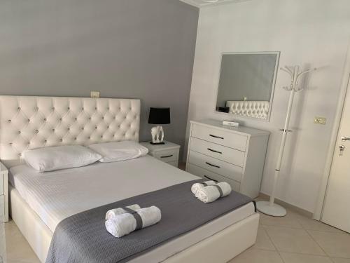 a white bedroom with a bed with towels on it at Marinela Apartment in Sarandë