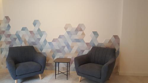 two chairs and a table in a room with a geometric wall at Hotel Victori in Es Castell