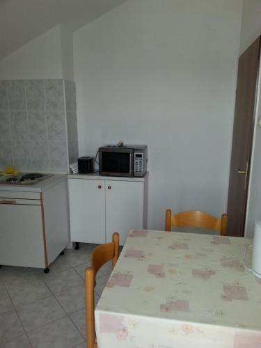 a small kitchen with a table and a microwave at Guesthouse Lidija in Kukljica