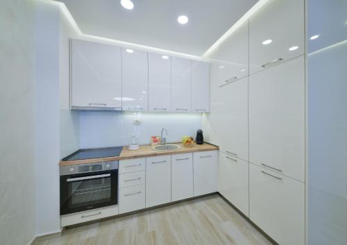a white kitchen with white cabinets and a sink at Brand New Apartments - free parking in Sveti Stefan