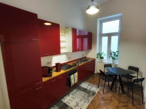 eine Küche mit roten Schränken und einem Tisch mit Stühlen in der Unterkunft Centrally-Located authentic apartment in Wien