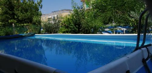 uma piscina azul com um edifício ao fundo em Annabella's Country House em SantʼAntonio Abate