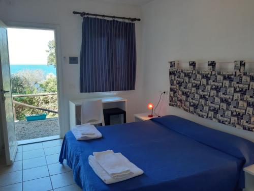 a bedroom with a blue bed and a large window at Hotel Grotte del Paradiso in Portoferraio