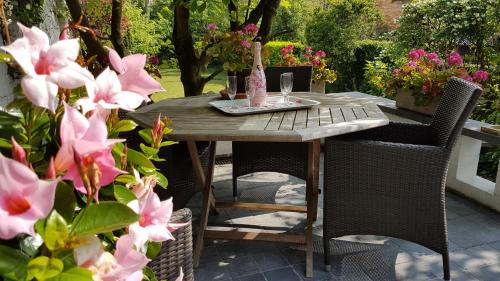 een houten tafel met stoelen en bloemen op een patio bij B&B Lieven Bauwens in Gent