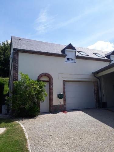 a white house with a garage with a driveway at la ville à la campagne in Lisieux