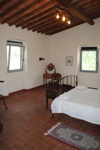 a bedroom with a bed and a table and two windows at Agriturismo Fattoria di Malavolta in Florence