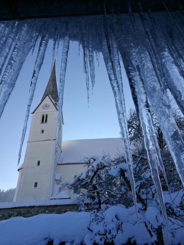 a church steeple with icicles on it in the snow at Gasthof Oberwirt in Lend