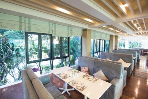 ein Restaurant mit Sofas, einem Tisch und Fenstern in der Unterkunft The Mantrini Chiang Rai in Chiang Rai