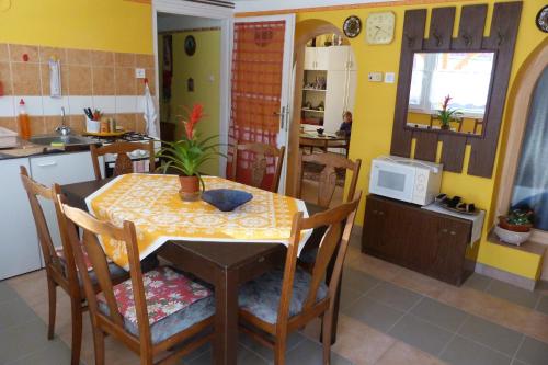 una cocina con mesa y sillas y una cocina con paredes amarillas. en Nagymama Házikója, en Tiszasas