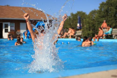 un garçon dans une piscine avec ses pieds dans l'eau dans l'établissement Village Historique de Val-Jalbert, à Chambord