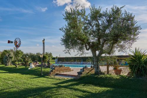 a park with a tree and a swimming pool at CASA VACANZE ARCOBALENO in Grosseto