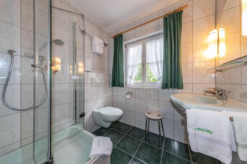 uma casa de banho com uma banheira, um WC e um lavatório. em Almroeserl em Mittenwald