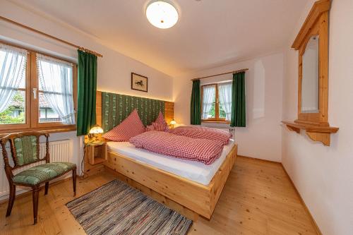 a bedroom with a bed and a chair and windows at Almroeserl in Mittenwald