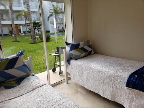 een slaapkamer met 2 bedden en een glazen schuifdeur bij CASA BAY BEACH RETREAT in Sidi Rahal